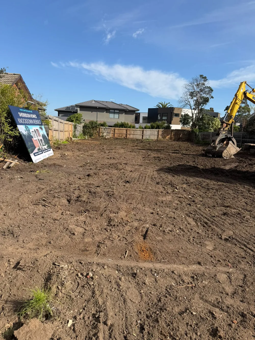 Earthmoving equipment beside a cleared residential block